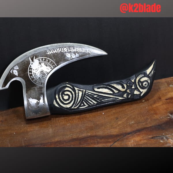 Engraved crescent axe: A sweeping crescent head decorated with runic lettering and an animal motif. The curved dark handle carries contrasting carved scrolls for a distinctive profile.